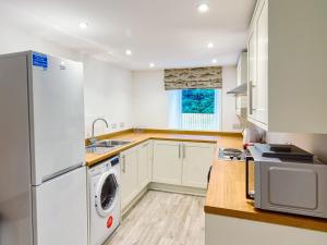 a kitchen with white cabinets and a washer and dryer at Wester Caiplich - Uk30261 in Cray