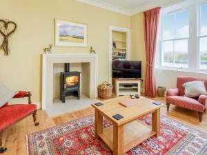 a living room with a fireplace and a table at Broomrigg Farmhouse in Pencaitland