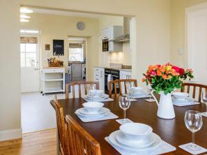 a dining room table with chairs and a vase of flowers at Broomrigg Farmhouse in Pencaitland