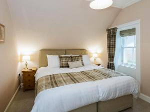 a bedroom with a large bed and a window at Broomrigg Farmhouse in Pencaitland