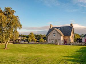 a large white house with a large grass field at Broomrigg Farmhouse in Pencaitland