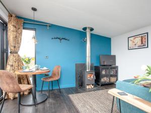 a living room with a blue wall with a wood stove at Stargazing Retreat - Uk32423 in Merton