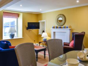 a living room with yellow walls and a table and chairs at 1 The Reading Room Cottages - Uk37359 in Barningham