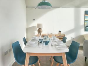 a dining room table with blue chairs and a white table with wine glasses at The Summer House in Leurbost