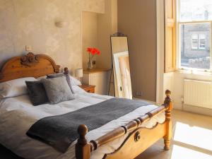 a bedroom with a large wooden bed with pillows at Purves Cottage in Allanton