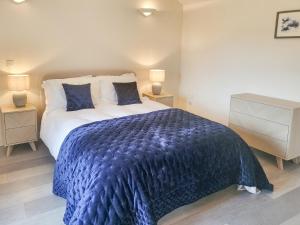 a bedroom with a large bed with a blue blanket at The Summer House in Leurbost