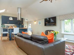a living room with a leather couch and a kitchen at Meadowside in Saint Mawes