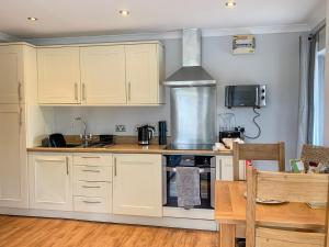 a kitchen with white cabinets and a stove at Rosemary Cottage-uk42032 in Highampton