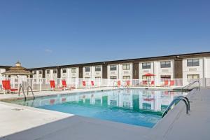 a large swimming pool with red chairs and a building at The Lux Hotel & Conference Center, Ascend Hotel Collection in Waterloo