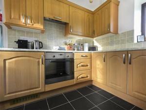 a kitchen with wooden cabinets and a stove top oven at The Hideaway in Kilve
