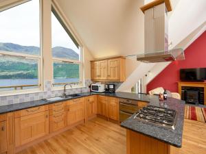 een keuken met houten kasten en een groot raam bij Skye Fall in Letterfinlay