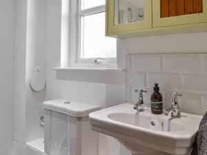 uma casa de banho branca com um lavatório e uma janela em Newton Cottage em Leitholm