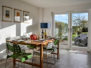 a dining room with a wooden table with green chairs at The Cottage in Leitholm