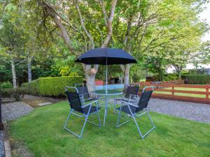 un tavolo con sedie e un ombrellone in un cortile di Black Rock Cottage a Culbokie