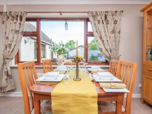 jadalnia ze stołem i żółtą tkaniną w obiekcie Black Rock Cottage w mieście Culbokie