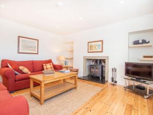 a living room with a red couch and a tv at Braefoot in Fortrose