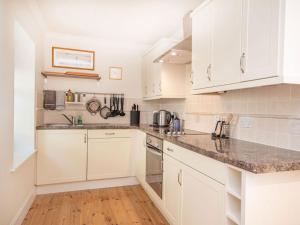 a kitchen with white cabinets and marble counter tops at Braefoot in Fortrose