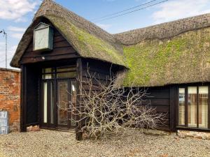 a house with a thatched roof with a plant at Bushton Barn in Royal Wootton Bassett