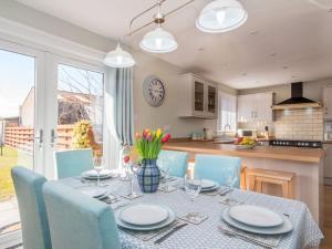 a dining room table with blue chairs and a kitchen at Raasay in Dornoch