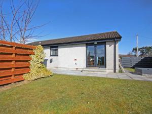 a house with a wooden fence in front of a yard at Raasay in Dornoch