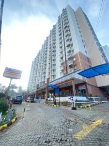 a large apartment building in front of a street at Cibubur Village Apartemen by Ar-Ramadhan in Cibubur