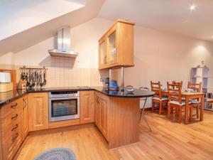 a kitchen with wooden cabinets and a table and chairs at Birds Eye View in Dornoch