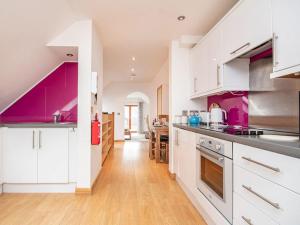 a kitchen with white cabinets and purple accents at The Hive in Dornoch
