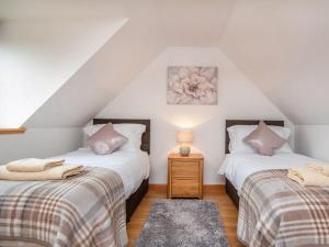 two twin beds in a attic room with a lamp at The Hive in Dornoch