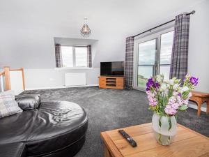a living room with a couch and a vase of flowers on a table at On The Beach-uk7465 in Balintore