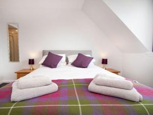 a bedroom with a large bed with purple pillows at On The Beach-uk7465 in Balintore