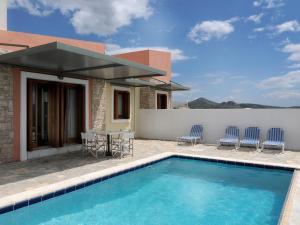 a pool with chairs and a table and a house at Karayiannis Villas in Nafplio