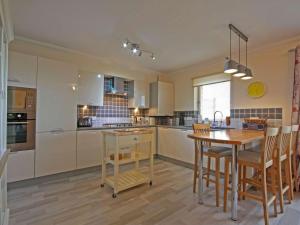 a kitchen with a wooden table and a dining room at Fairway Apartment in Nairn