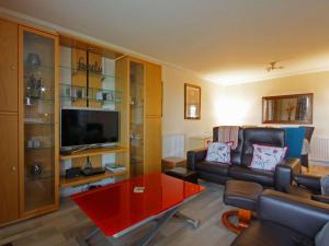a living room with a couch and a flat screen tv at Fairway Apartment in Nairn