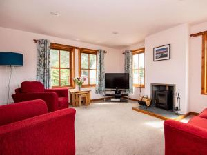 a living room with red furniture and a flat screen tv at Fernabeg in Edderton