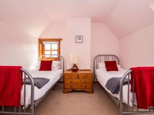 two beds in a room with red pillows at Fernabeg in Edderton