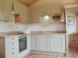a kitchen with white cabinets and a microwave at Shepherds Lodge-ukc2358 in Buildwas