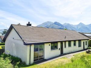 una casa blanca con montañas en el fondo en Tighur en Kintail