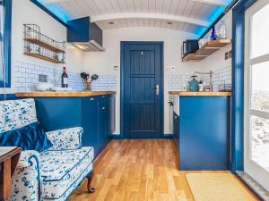a kitchen with blue walls and a blue door at The Drift Shepherds Hut - Ukc6878 in Aultgrishin