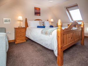 a bedroom with a large wooden bed and a window at Sunnyside Cottage in Embo
