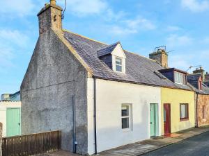 an old white house with a grey roof at Sunnyside Cottage in Embo