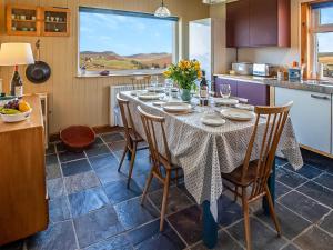 a kitchen with a table with chairs and a window at Smithy Burn Croft in Rhilochan