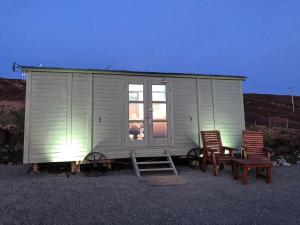 a tiny house with two chairs and a table at The Drift Shepherds Hut - Ukc6878 in Aultgrishin