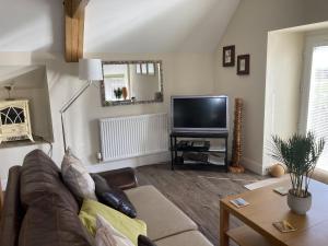 sala de estar con sofá y TV en Cuthbert Cottage - W43224, en Belford