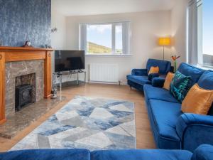 a living room with a blue couch and a fireplace at Sunny Hill - Ukc6884 in Aultgrishin