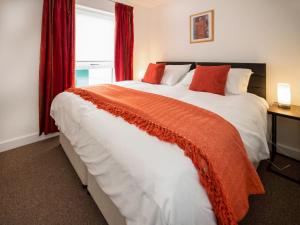 a bedroom with a large bed with red curtains at Thistledown in Dornoch
