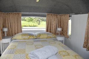 um quarto com uma cama com almofadas e uma janela em Evi the school bus at Oromahoe Downs Farm em Puketona