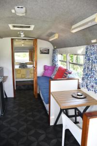 Cette caravane comprend un lit et une table. dans l'établissement Evi the school bus at Oromahoe Downs Farm, à Puketona