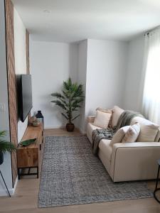 un salon avec un canapé blanc et une plante dans l'établissement Trotamundos, apartamento nuevo en el centro, à Cordoue