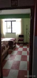 a room with a checkered floor with a bed and a window at HOSTAL ETERNA PRIMAVERA in Copacabana