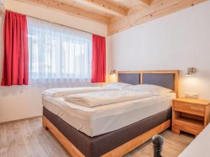 a bedroom with a bed and a window with red curtains at Blick auf den Rettenstein Top 1 und 2 in Kirchberg in Tirol